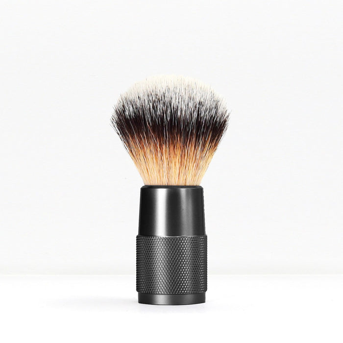 Shaving brush with light bristles and black knurled handle on white background.