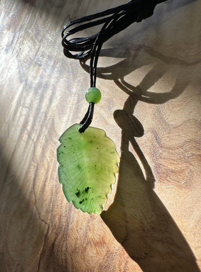 Canadian green jade leaf pendant 25.5mm on a black cord with a small round bead above the leaf.