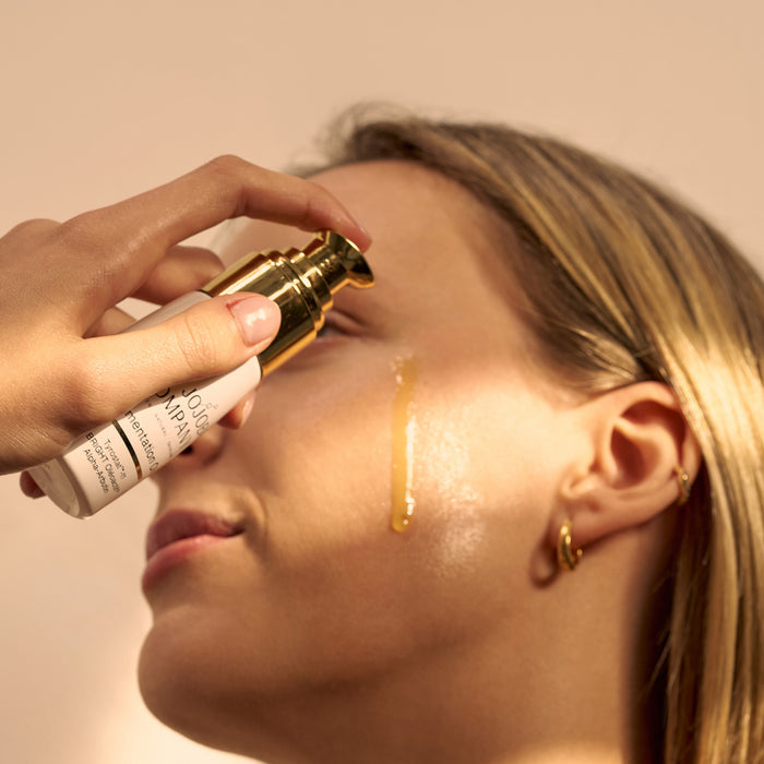 Person applying The Jojoba Company's Pigmentation Oil to their face with a neutral background