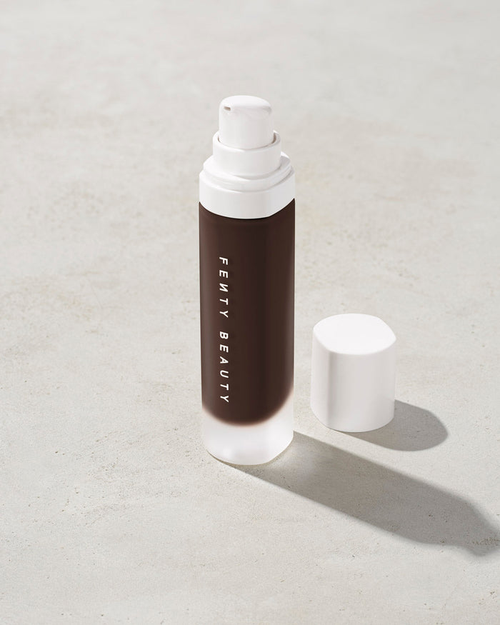 open bottle of Fenty Beauty Pro Filt'r Soft Matte Longwear Foundation with pump dispenser in shade 498 on concrete background