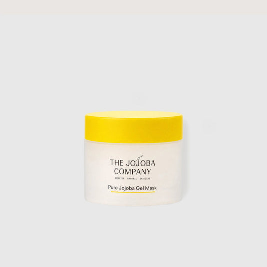 A jar of The Jojoba Company Pure Jojoba Gel Mask with a bright yellow lid and a white jar, centered on a light gray background.
