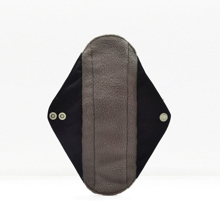 Single reusable panty liner with soft fleece interior and dark outer fabric with snap fasteners