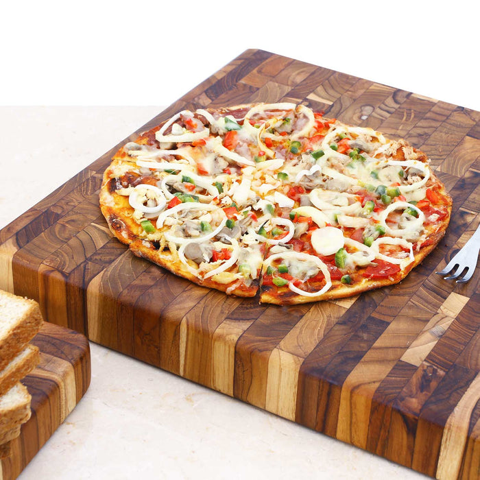 Pizza and fork sitting on an end grain cutting board placed on a white counter