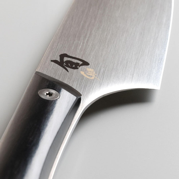 Close up of the hilt of a 8 inch Shun chef knife on a light grey background