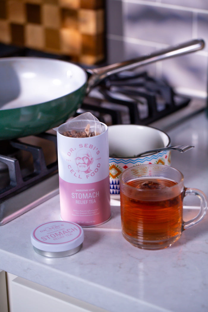 Dr. Sebi's Stomach Relief Tea displayed with brewed cup in kitchen setting.