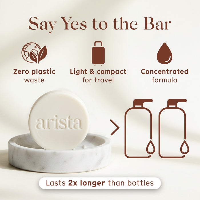 Round white shampoo bar resting on a marble dish with a soft beige background and the caption Lasts 2x longer than bottles