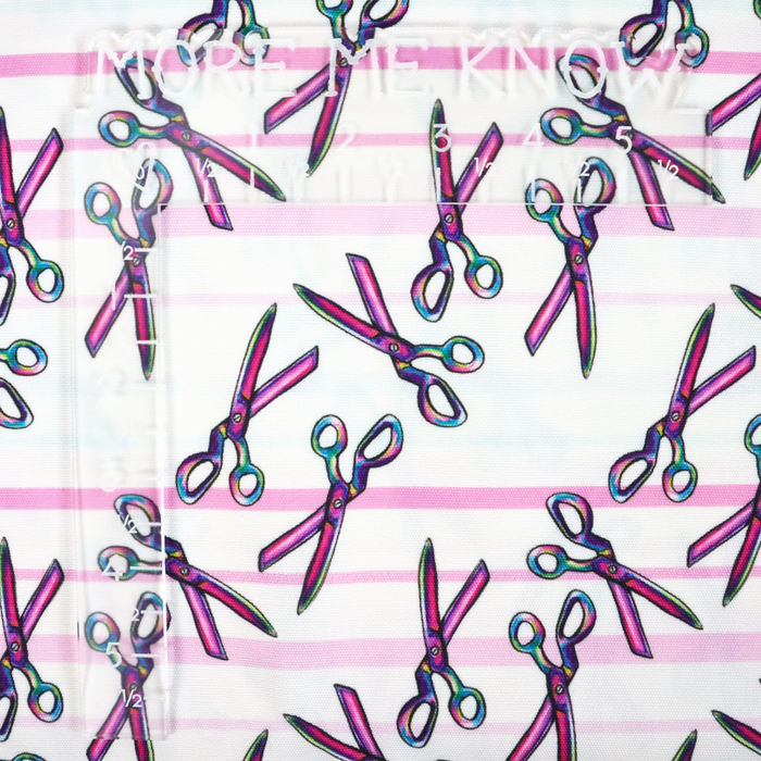 This ReNew Canvas print is of a rainbow scissors design over light blue, pink, and white stripes. This photo has an L shaped ruler for scale.