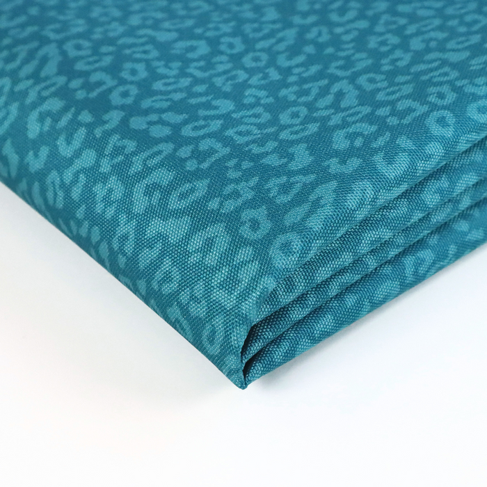 This printed WPC-Lite has a repeating light teal leopard print design with a deep saturated teal background. This photo shows the fabric folded.