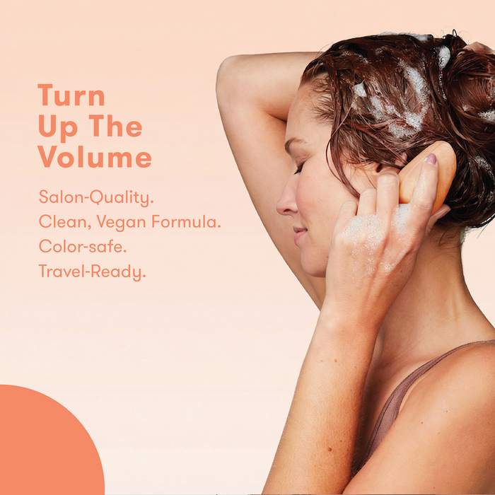 Person using shampoo bar on hair with text. Turn up the volume. Salon-quality. Clean, Vegan formula. Color-safe. Travel ready.