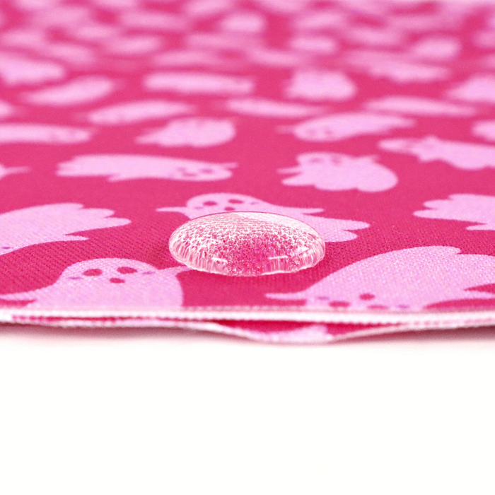 This printed WPC-Lite has ghosts that are featured in light pink on top of a deeper pink background. This photo shows a water drop on the fabric.