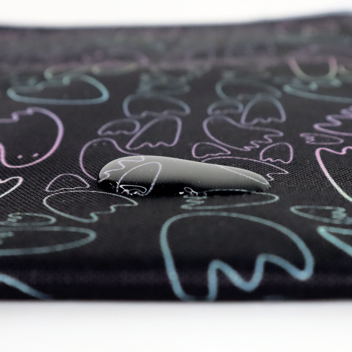 This printed WPC has pastel rainbow ghost outlines in different sizes on a black background. This photo shows a water drop on the fabric.